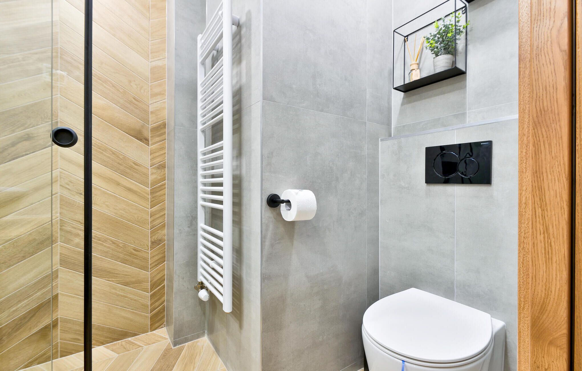 Een moderne badkamer met een douche, toilet en een radiator.