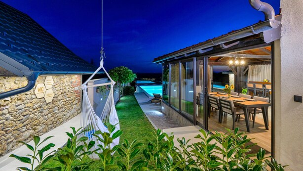 Eine moderne Außenpatio mit Pool, einer Hängematte und einem Essbereich mit Blick auf den Pool.