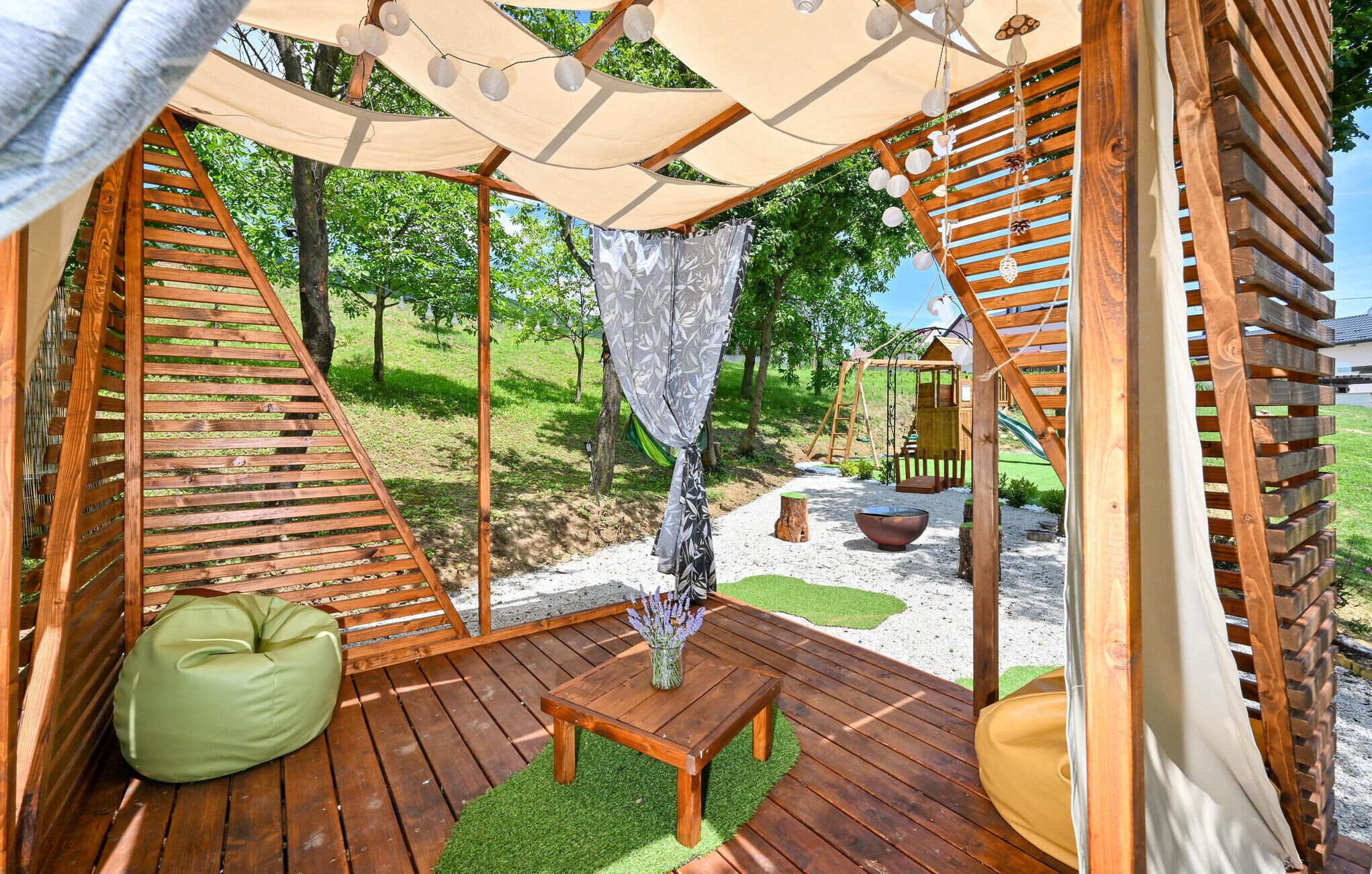 A wooden deck with a swing set, a small table, and a green bean bag.
