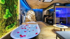 Ein Spa-Raum mit einer großen Badewanne, einer Holzwand mit grünem Moos und einem modernen Deckenstil.