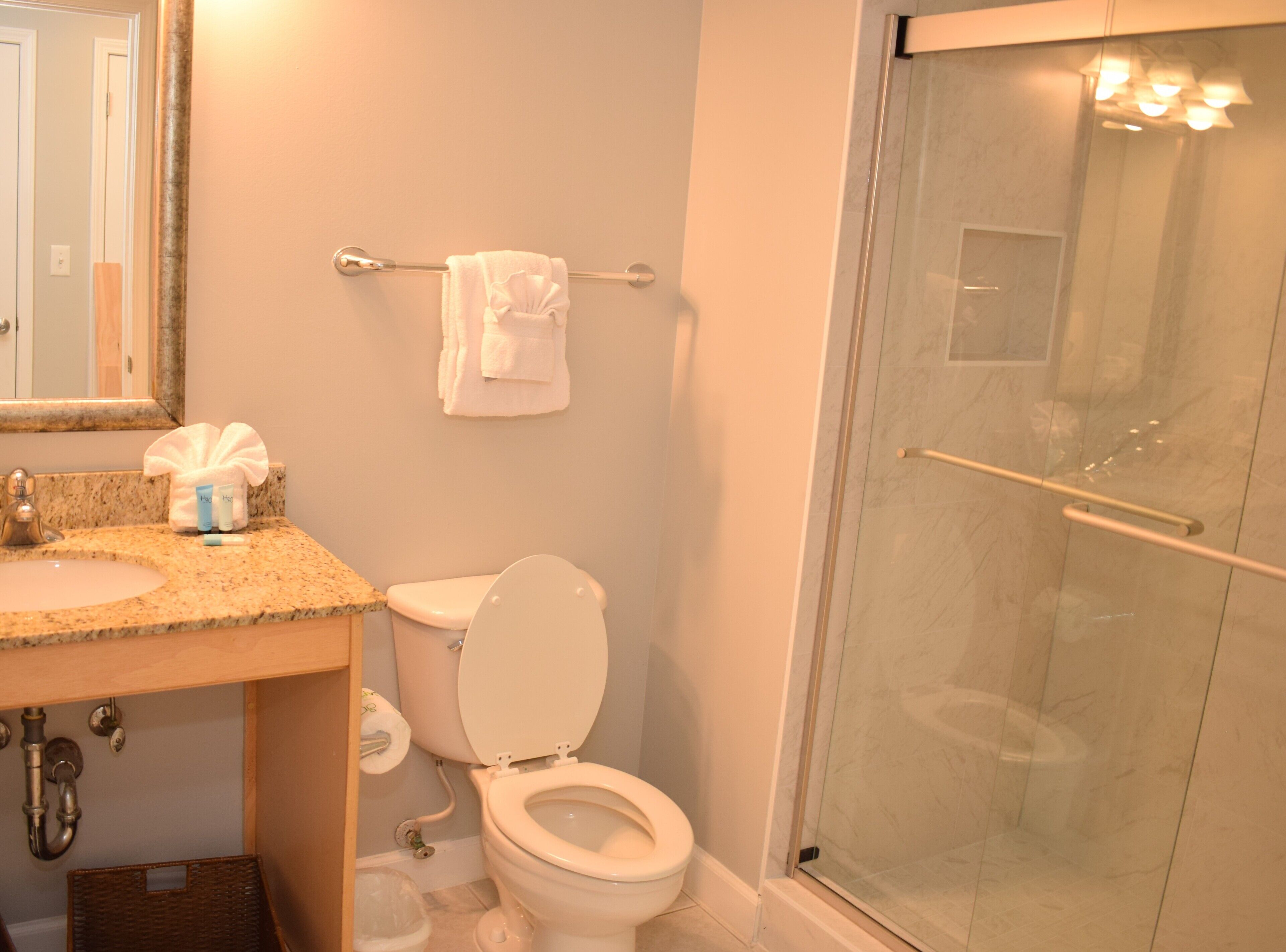 A bathroom with a sink, toilet, and a glass-enclosed shower.