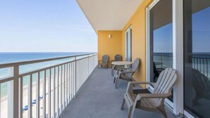 Een balkon met uitzicht op de oceaan, met twee tafels en vier stoelen.
