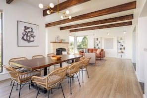 A spacious dining area with a wooden table and wicker chairs, a fireplace, and a cozy seating area with a sofa and armchairs. - Peaceful Sedona Sanctuary I Private Creek Access (Sedona)
