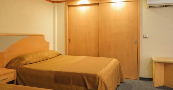 A hotel room with a bed, a wooden wardrobe, a bedside table, and a small desk. - Hotel Milan CDMX (Mexico City)