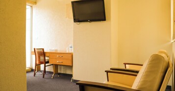 Une chambre d’hôtel équipée d’un bureau, d’une chaise, d’un téléviseur fixé au mur et d’une fenêtre.