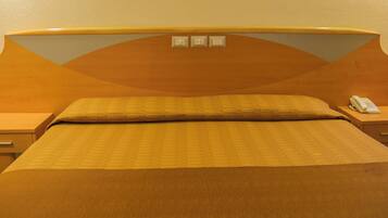 A hotel room with a large bed, a wooden headboard, two bedside tables, and a telephone on one of the tables.