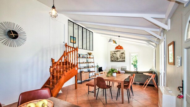 Un vaste espace de vie agrémenté d’un escalier en bois, d’une table à manger avec des chaises et d’un coin salon confortable.