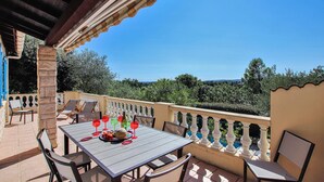 Une terrasse avec une table dressée pour le repas, des sièges d’extérieur et une vue sur le paysage.