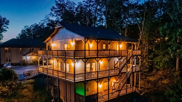 Une cabane en bois à deux étages, dotée d’un balcon et entourée d’arbres.