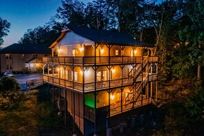 En toetages træhytte med balkon, omgivet af træer.