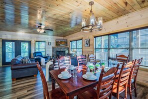 A spacious living room with a fireplace, large windows, and a dining area with wooden chairs and a table set for four. - Views Putt putt Theater Hot Tub Arcade Pool (Pigeon Forge)