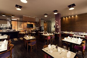 Un ristorante con diversi tavoli apparecchiati per consumare, una zona cucina e uno schermo televisivo.