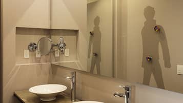 A modern bathroom with two sinks, a large mirror, and a tray with toiletries.