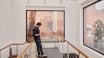 A man standing on a staircase with a city view through a large window.