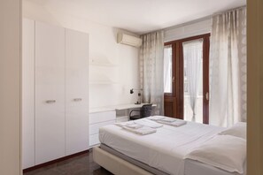Une chambre à coucher comprenant un lit, un bureau, une chaise, une armoire et une fenêtre avec des rideaux.