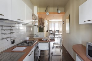Une cuisine moderne dotée d’un îlot central, d’appareils électroménagers en acier inoxydable et d’un coin repas avec une table et des chaises.