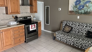 A kitchen with wooden cabinets, a black stove, and a tiled floor. - Sunny Apartments a block from Warm Mineral Springs. Unit 3 (North Port)