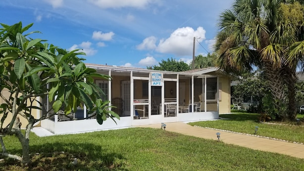 A covered outdoor seating area with a sign reading "Welcome to Sunny Apt." - Sunny Apartments a block from Warm Mineral Springs. Unit 3 (North Port)