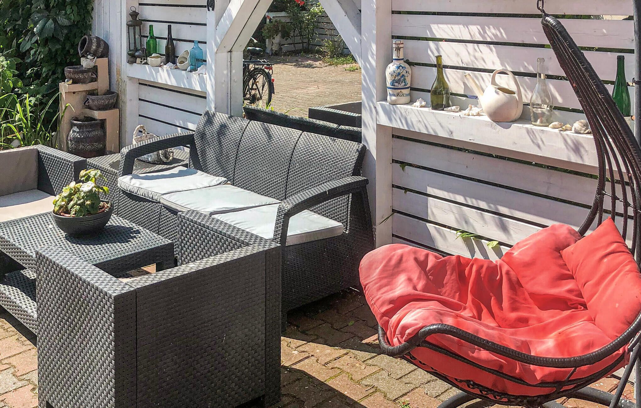 Eine Außenpatio mit Korbmöbeln, einem Hängesessel und einem Regal mit verschiedenen Gegenständen.