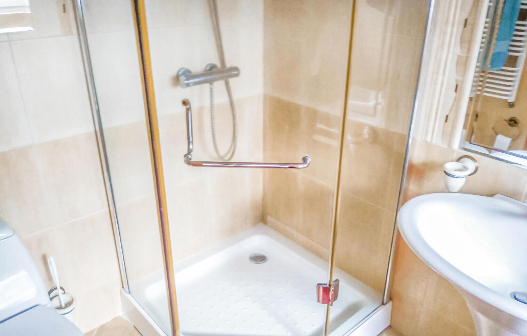 Une douche fermée par des parois en verre, équipée d’un pommeau de douche à main, d’un autre pommeau de douche à main et d’un troisième pommeau de douche à main.