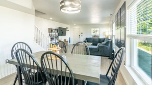 Una cucina moderna con un tavolo da pranzo e sedie, un lampadario e vista sull'esterno grazie a ampie finestre.