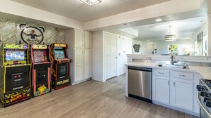 Una cucina moderna con mobili bianchi, lavastoviglie in acciaio inox e giochi arcade.