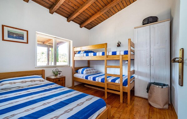 A room with a bunk bed, a single bed, a wardrobe, a window, and a small table with a plant. - Nice home in Sali with WiFi (Sali)