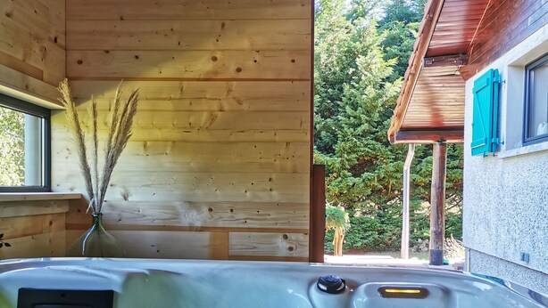 Una cabaña de madera con jacuzzi, paredes de madera y vistas a un bosque.