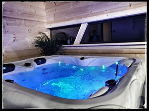 A hot tub with blue lighting inside a wooden cabin.
