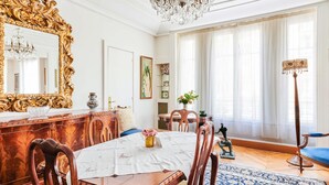 A dining room with a large ornate mirror, wooden furniture, a chandelier, and a patterned rug. - Appartement Carpette - Welkeys (Paris)