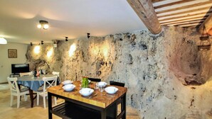 Un coin repas rustique avec un mur en pierre, une table en bois et des chaises.