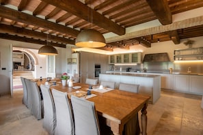 Una cocina amplia con una isla central, vigas de madera en el techo y un comedor con una mesa grande y sillas.