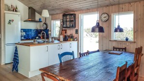 A kitchen with a wooden table and chairs, a refrigerator, and a clock on the wall. - Amazing home in Anholt with WiFi (Anholt)
