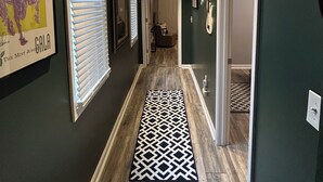 A hallway with dark walls, a patterned rug, and a ceiling light fixture. - Breaking Records - Steps from Paristown Hall (Louisville)