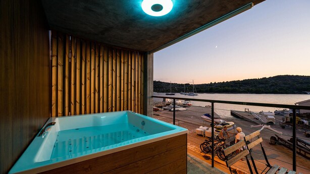A balcony with a wooden floor, a blue bathtub, and a view of a marina with boats. - Cozy home in Kaprije with kitchen (Kaprije)