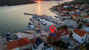 A coastal town with a marina, houses with red-tiled roofs, and a sunset over the water. - Cozy home in Kaprije with kitchen (Kaprije)