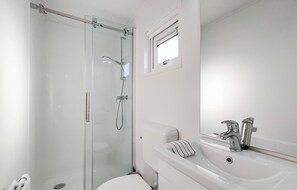 Bathroom features a glass-enclosed shower, handheld showerhead, and wall-mounted faucet.