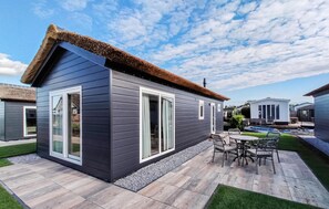 Enjoy a contemporary retreat with a thatched roof and large sliding glass doors, featuring a well-maintained patio with a dining area.
