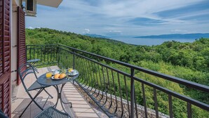 A balcony with a table set for breakfast, overlooking a lush green landscape and a body of water. - Awesome apartment in Labin with sauna (Labin)