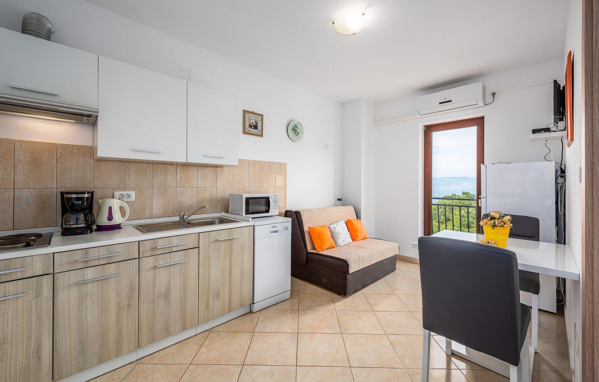 Een compacte keuken met moderne apparaten, een eethoek met een tafel en stoelen, en een balkon met uitzicht.