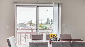 A dining area with a table and chairs, a window with curtains, and a view of a residential area.