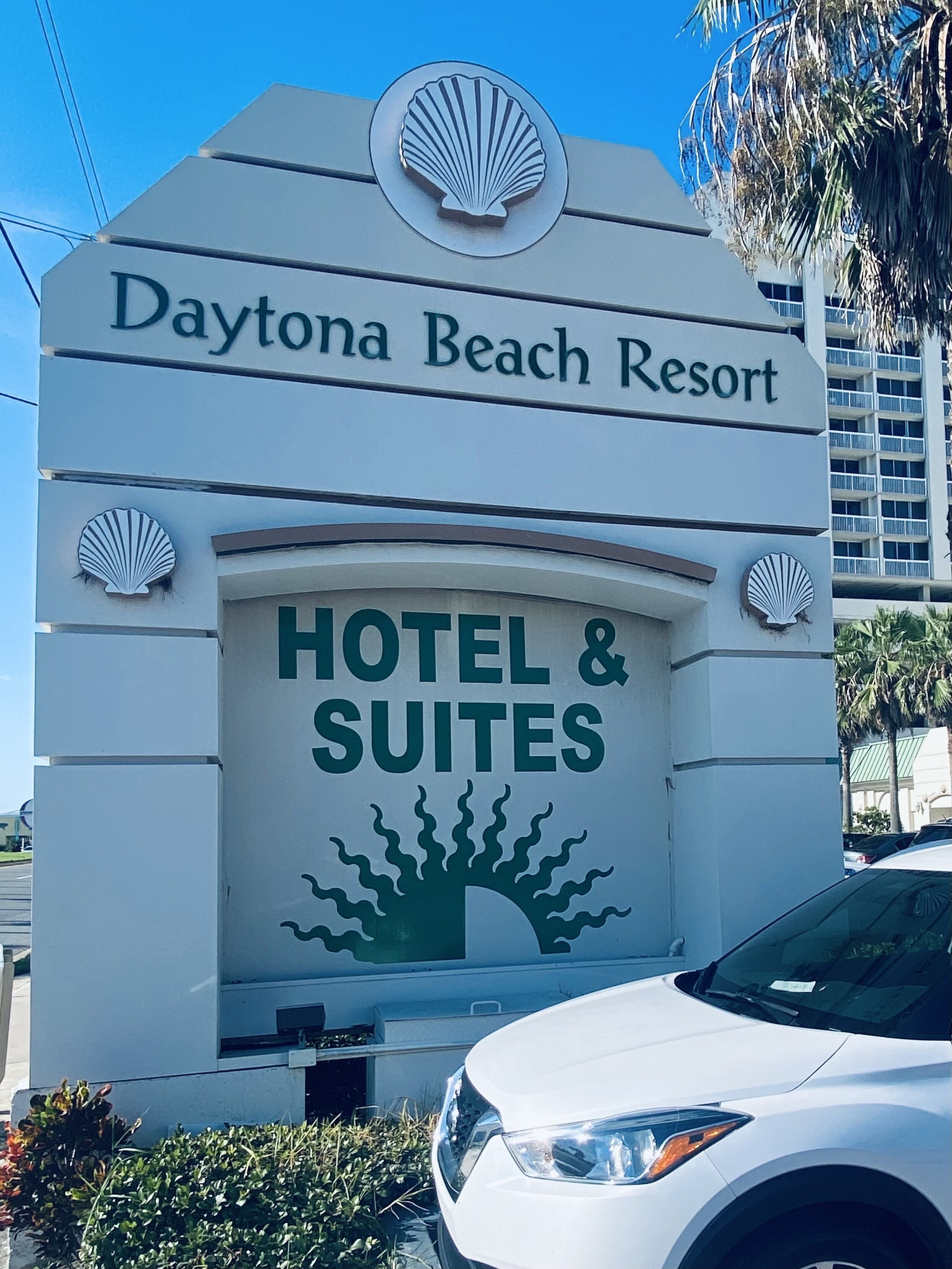 Placa do Daytona Beach Resort Hotel & Suites, com logotipo de concha e ilustração de árvore.