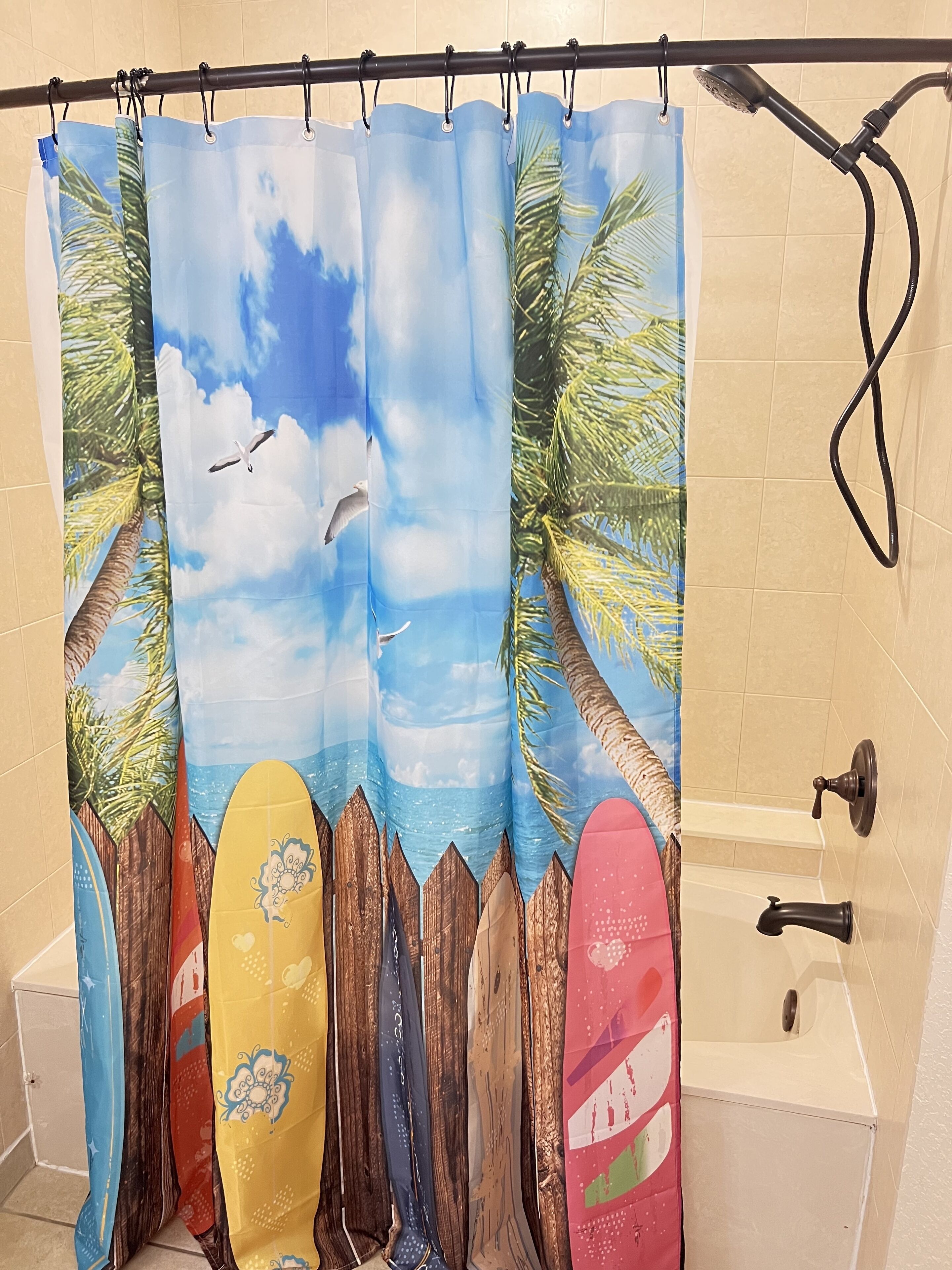 Een douchegordijn met een tropisch stranddecor, inclusief palmbomen en surfplanken.
