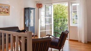 Una habitación con una mesa de comedor de madera, dos sillas, un armario y un ventanal con vistas a zonas verdes.