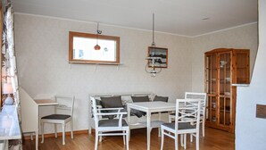 Un comedor con una mesa y sillas blancas, un armario de madera y una lámpara colgante.