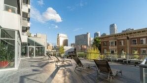 A rooftop terrace with sun loungers, potted plants, and a city skyline in the background. -  Prime location Downtown Vancouver (Vancouver)
