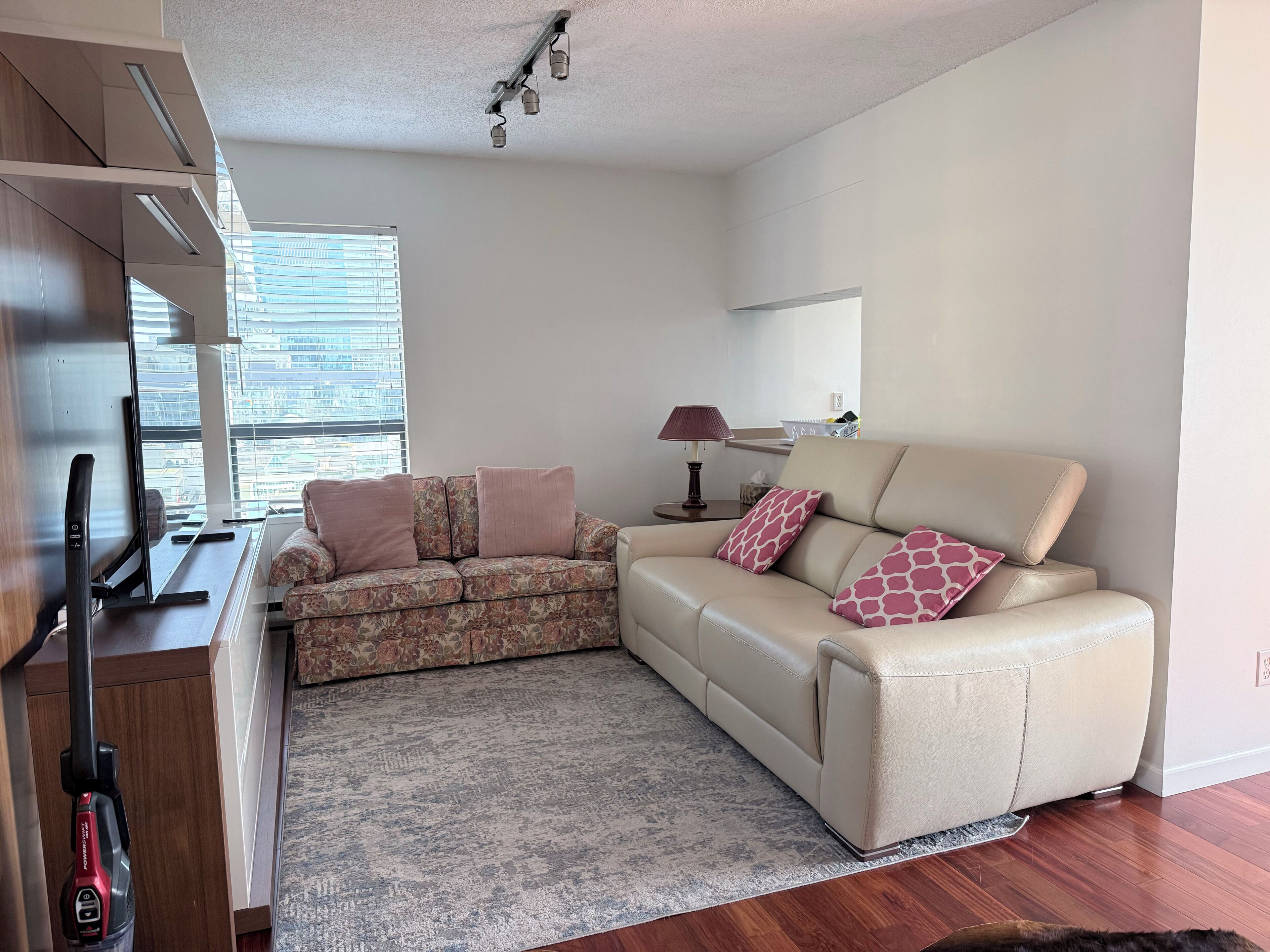 A modern living room with a sofa, a coffee table, a lamp, and a TV.