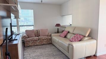 A modern living room with a sofa, a coffee table, a lamp, and a TV.