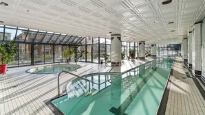An indoor swimming pool with a glass ceiling, tiled floors, and potted plants. -  Prime location Downtown Vancouver (Vancouver)