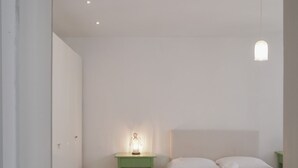 Une chambre à coucher minimaliste avec un lit simple, une table de chevet avec une lampe et un luminaire suspendu.